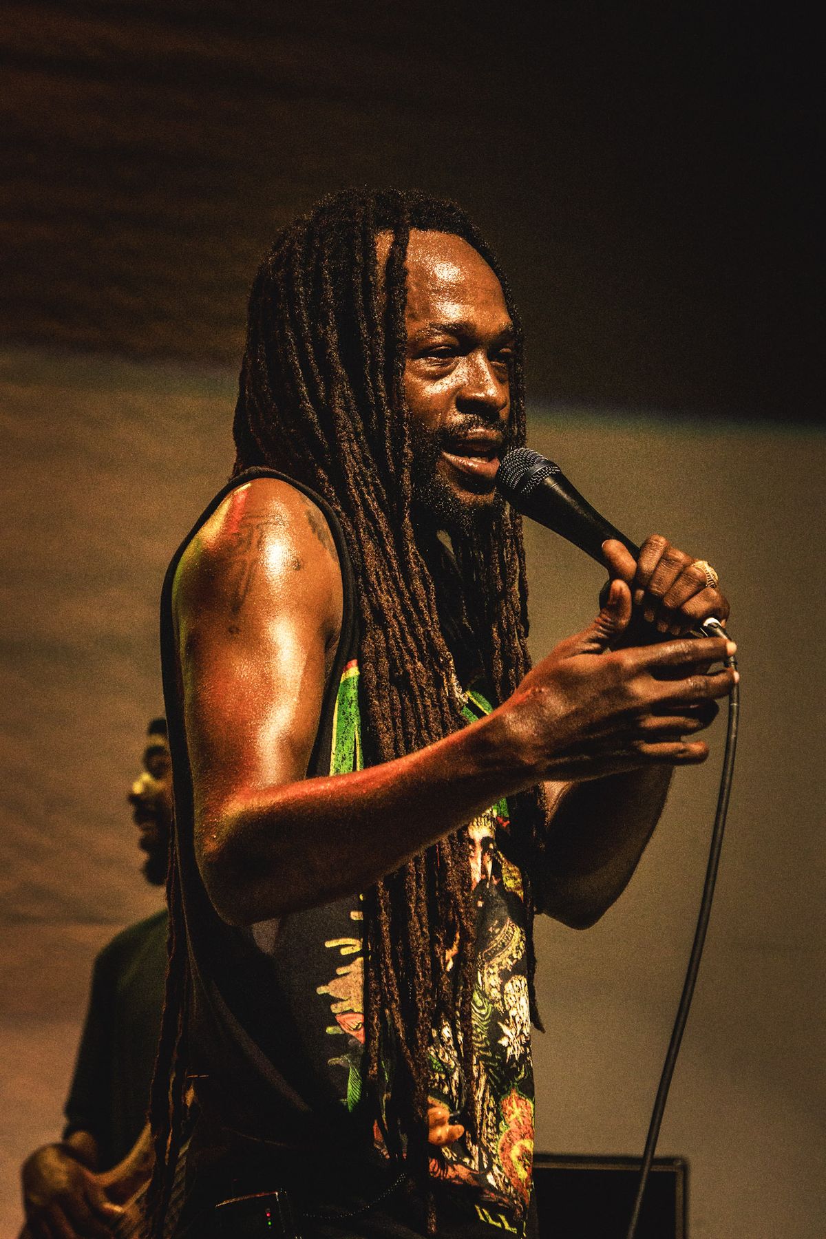 Vocalist with long locs singing into a microphone on stage
