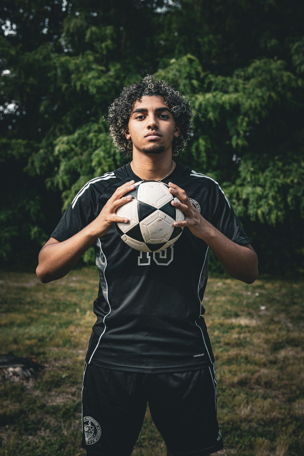 Soccer player in a black kit holding a ball with both hands