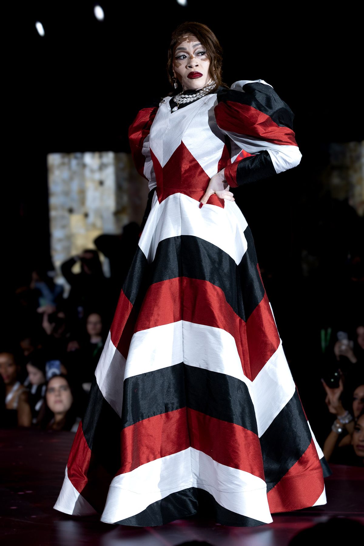 Model in a red, black and white chevron gown on the runway