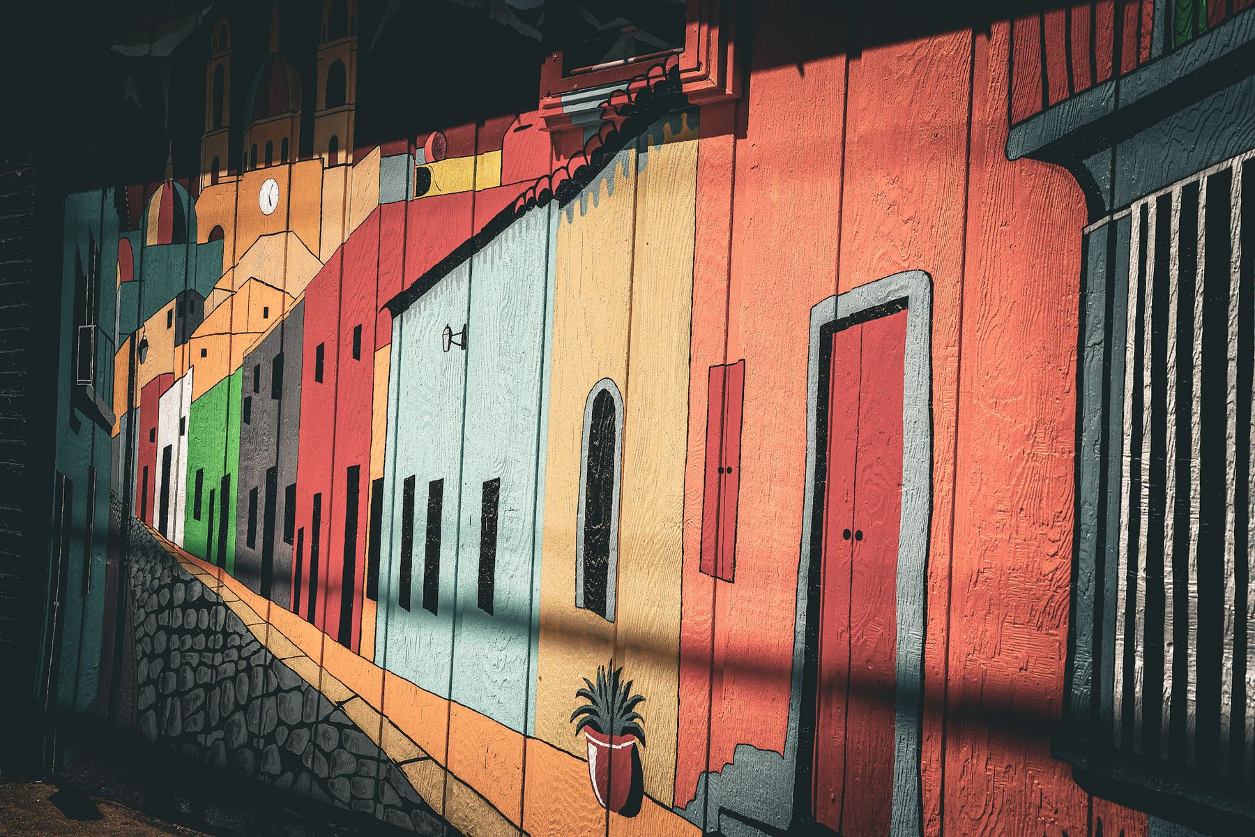 Colorful painted mural of a street of houses in light and shadow