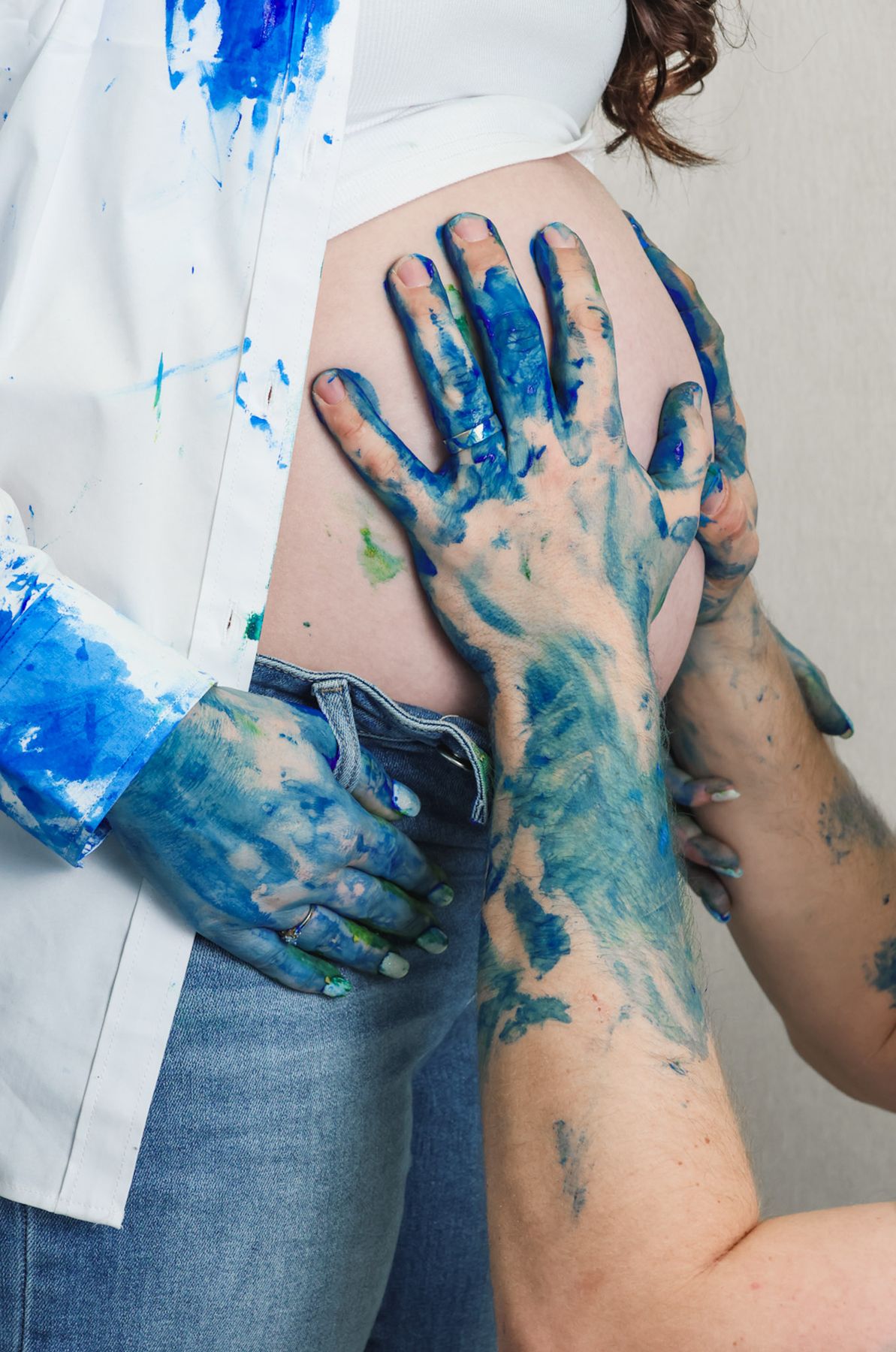 Hands covered in blue paint resting on a pregnant belly