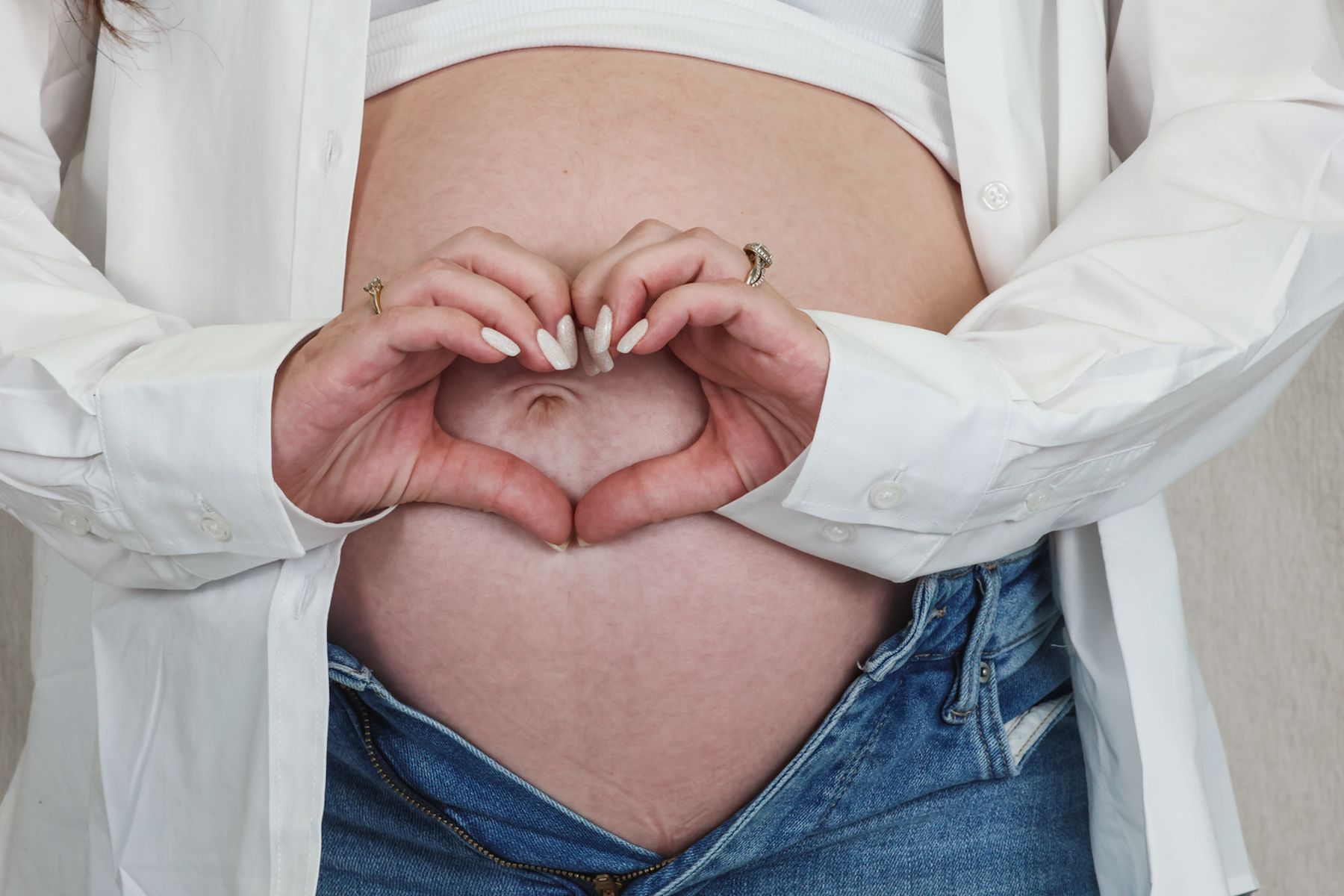 Hands forming a heart over a baby bump
