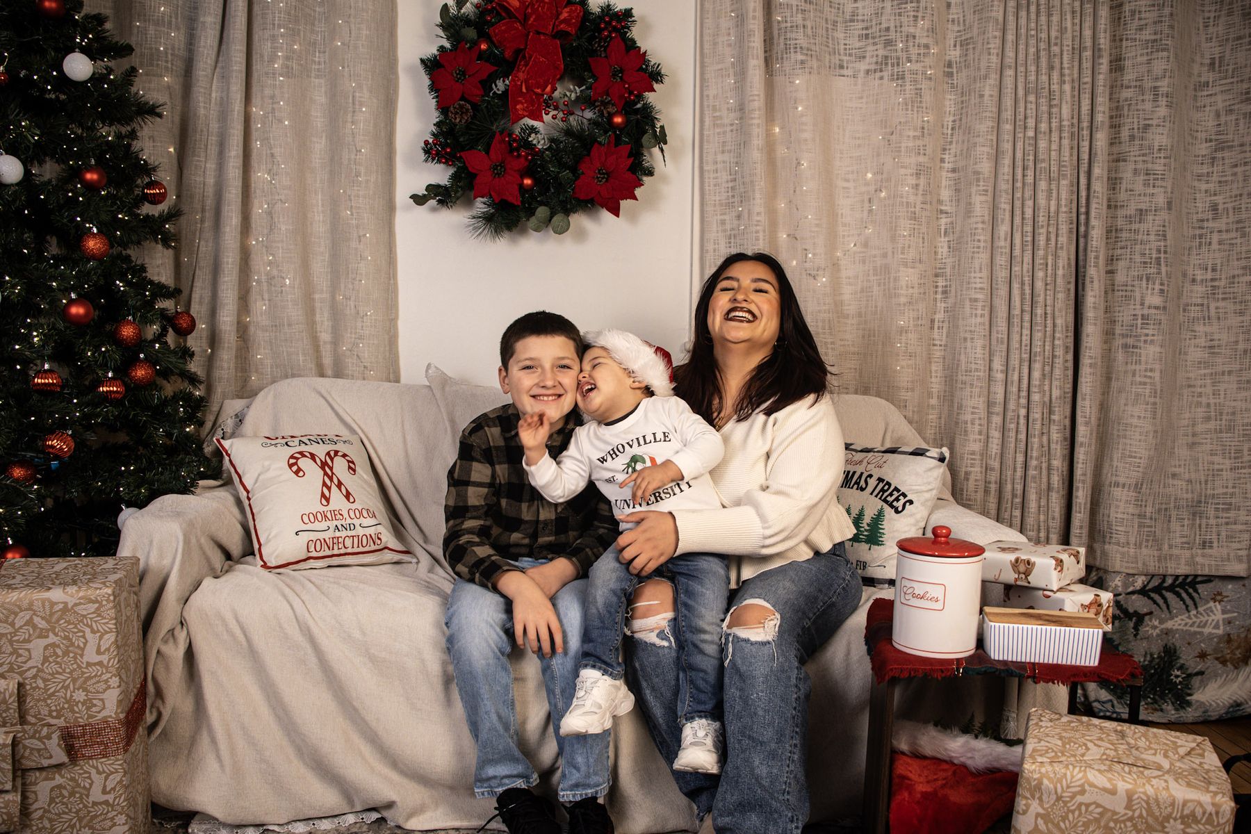 Parent and two children laughing together on a holiday-styled couch