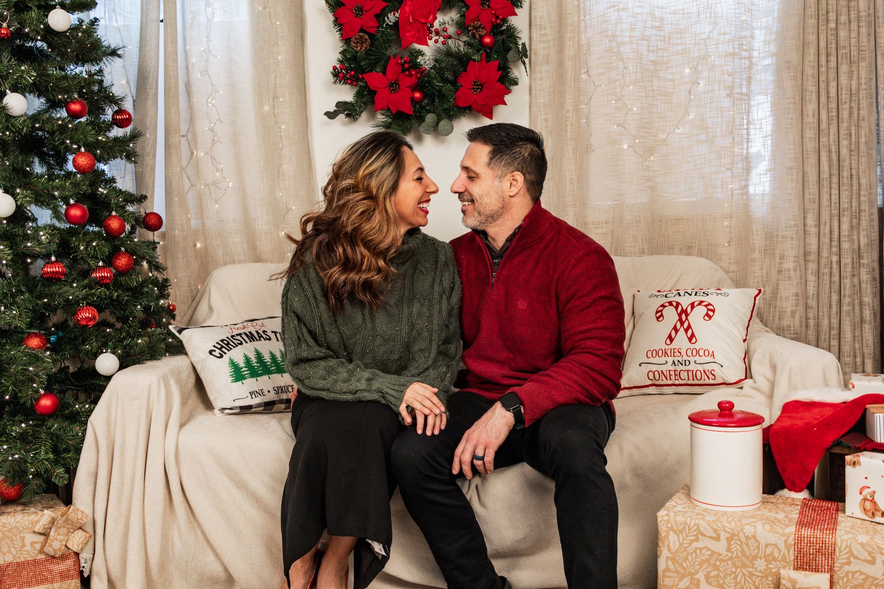 Couple sitting close together on a couch in a Christmas-themed setup